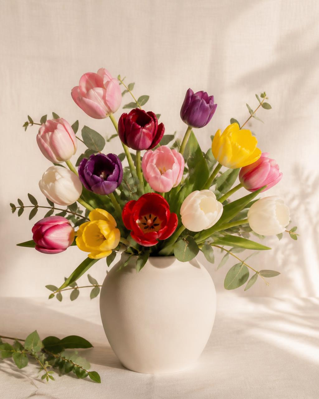 Gemengde tulpen in een matte crèmekleurige vaas